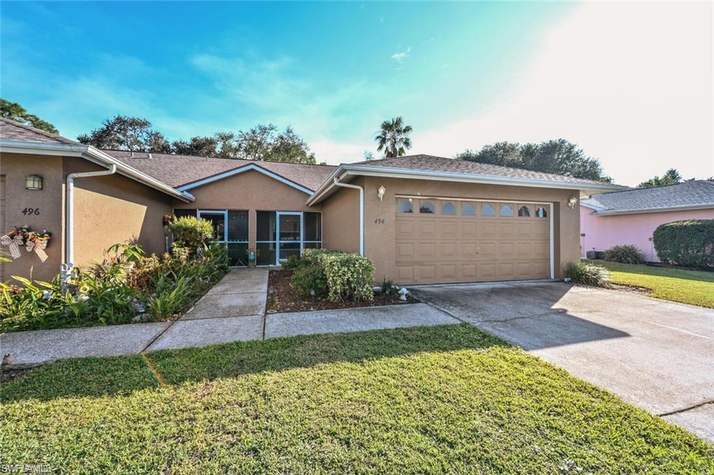 Ranch-style house with stucco siding, driveway, a front lawn, and an attached garage