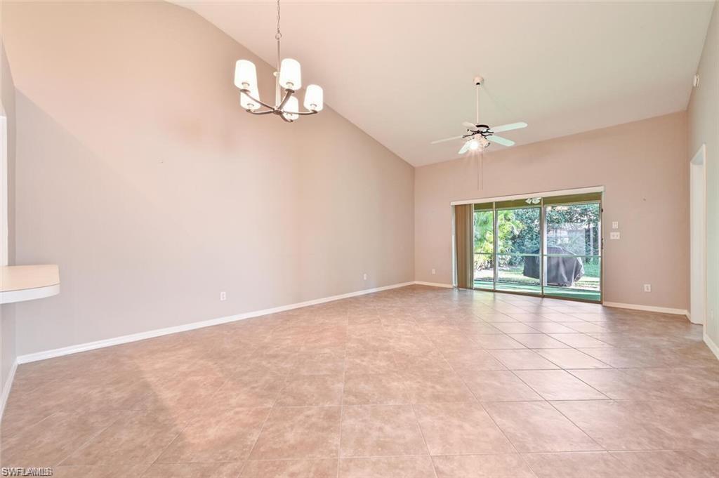 Spare room featuring lofted ceiling, a ceiling fan, a chandelier, and light tile patterned floors