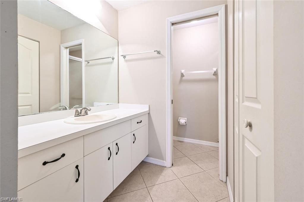Full bathroom with vanity, light tile patterned floors, and an enclosed shower