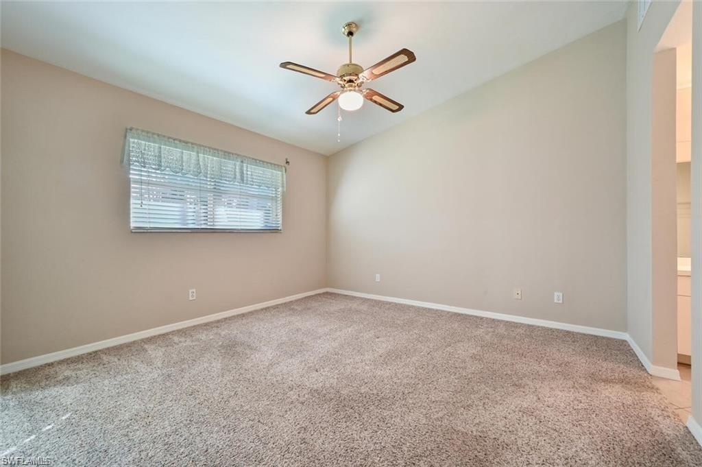 Spare room featuring light colored carpet, lofted ceiling, and ceiling fan