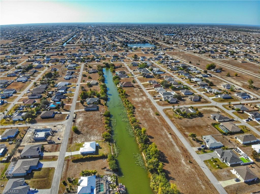 Aerial view of property and surrounding area featuring nearby suburban area and a large body of water