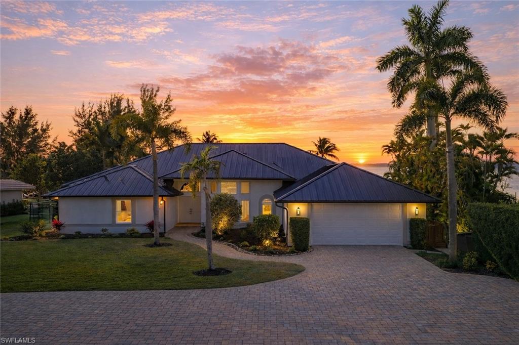 View of front facade featuring driveway, a front yard, a standing seam roof, and a garage