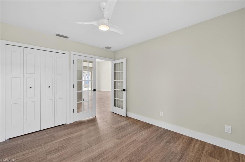 Unfurnished bedroom featuring french doors, wood finished floors, a ceiling fan, and a closet