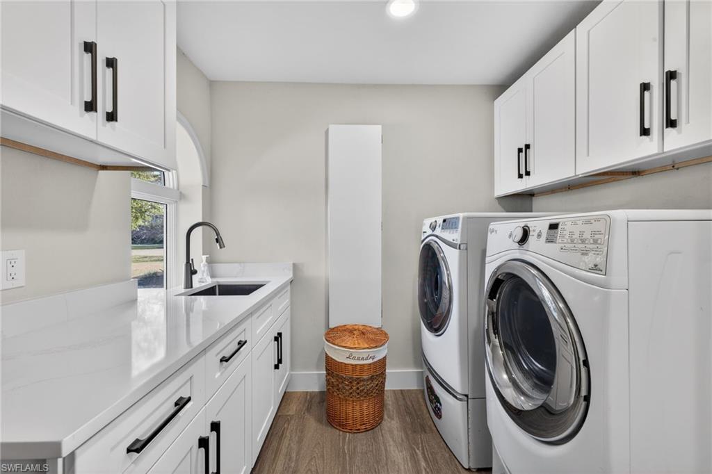 Laundry room with cabinet space, washer and dryer, dark wood finished floors, and recessed lighting