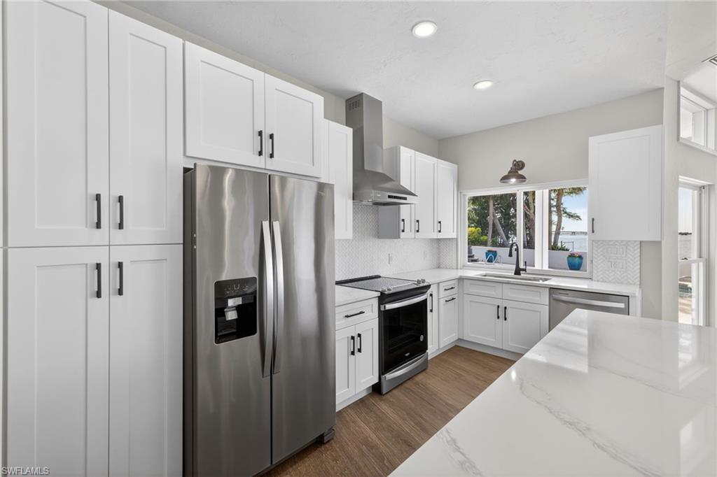 Kitchen featuring stainless steel appliances, white cabinets, dark wood-type flooring, decorative backsplash, and recessed lighting