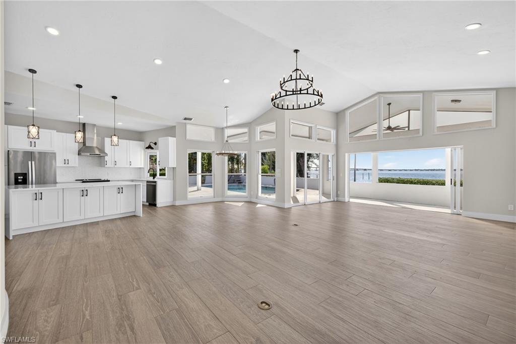 Unfurnished living room with a chandelier, a high ceiling, and light wood finished floors