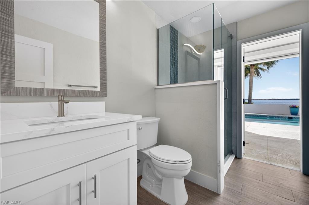 Full bath featuring a stall shower, vanity, dark wood-style flooring, and a water view
