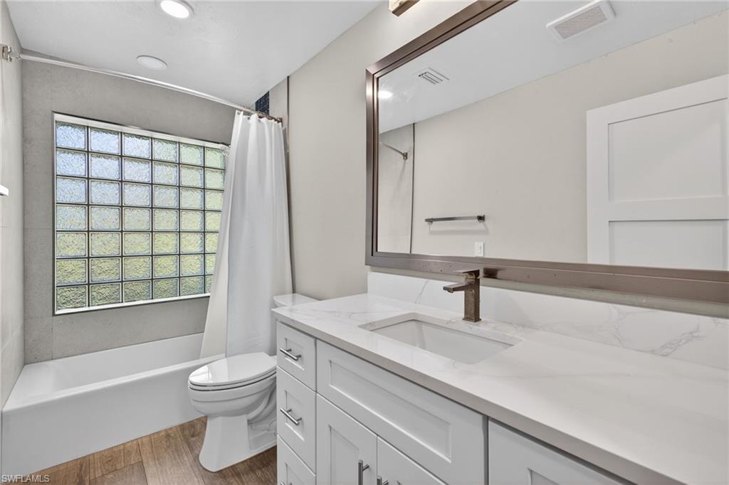 Full bathroom with vanity, shower / bath combination with curtain, dark wood-style floors, and recessed lighting