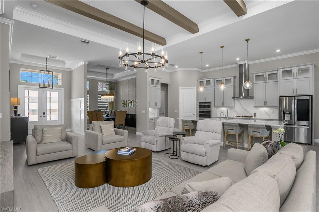 Living room featuring crown molding, hanging lights, wood finished floors, french doors, and a raised ceiling