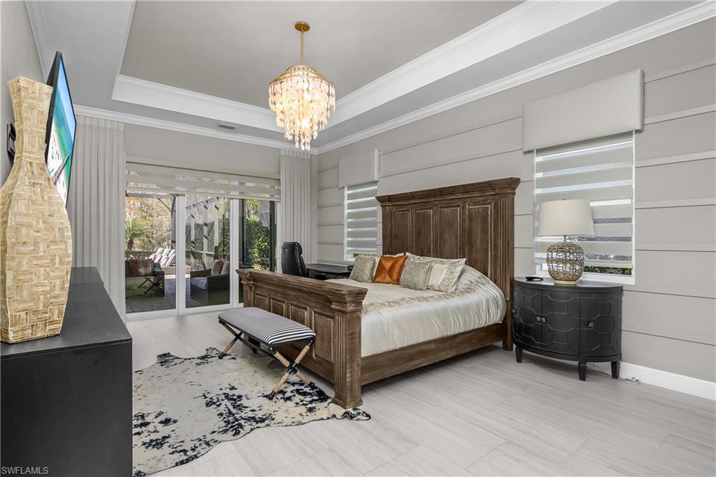 Bedroom featuring access to exterior, suspended lighting, a tray ceiling, and ornamental molding