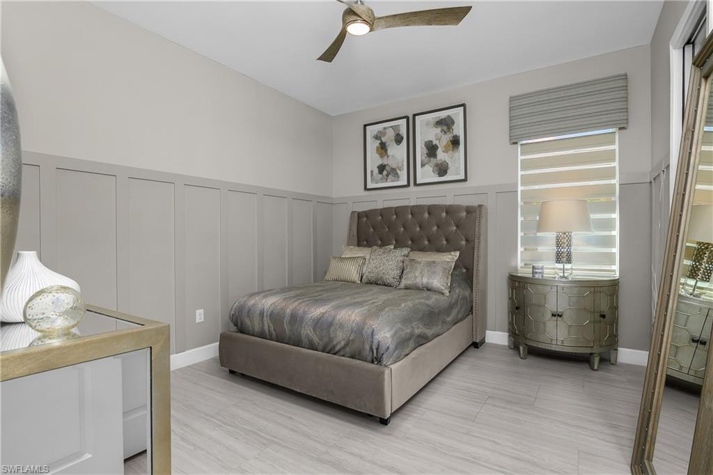 Bedroom featuring a decorative wall, a wainscoted wall, and ceiling fan