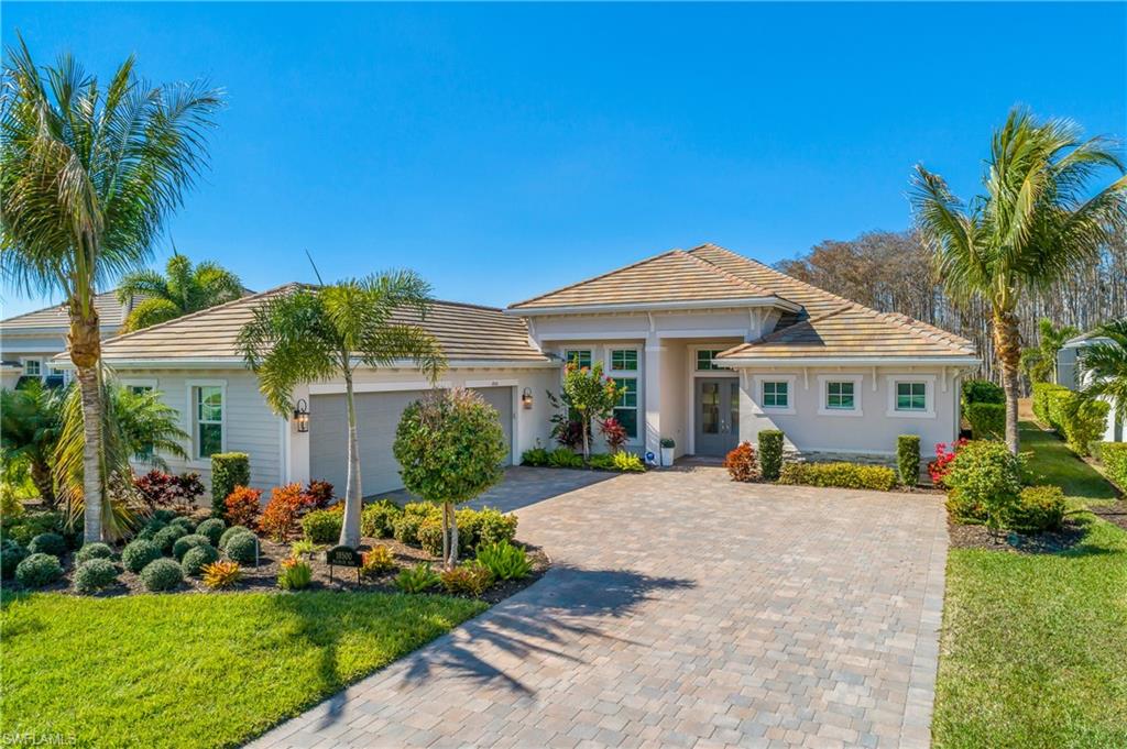 Single story home featuring a front lawn, decorative driveway, a tiled roof, and a garage