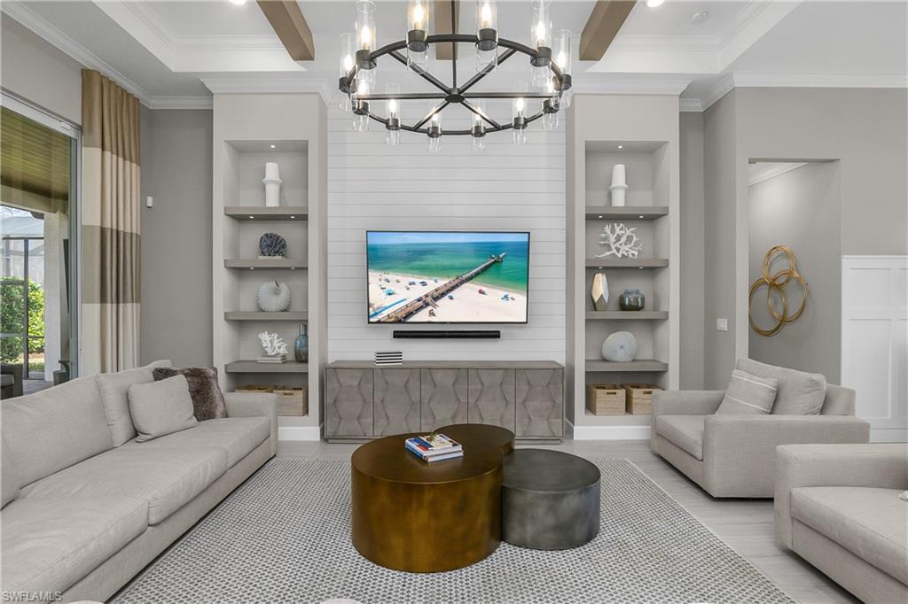 Living room with built in features, crown molding, beam ceiling, hanging lights, and wood finished floors