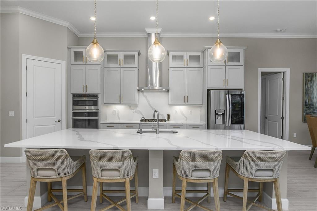 Kitchen with stainless steel appliances, a kitchen breakfast bar, backsplash, light stone counters, and a spacious island