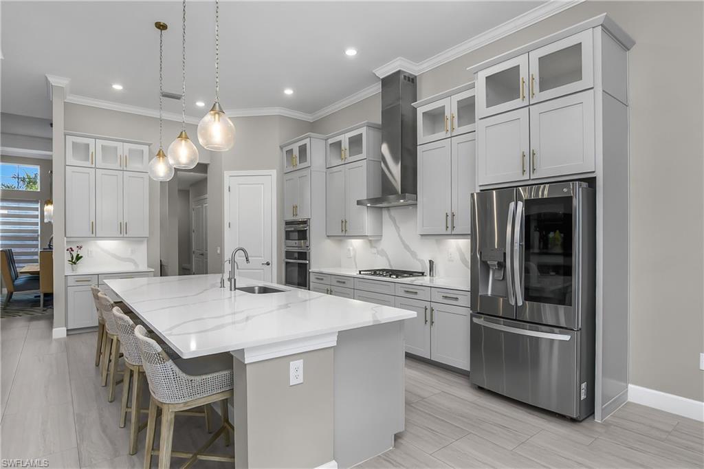 Kitchen with stainless steel appliances, glass fronted cabinets, decorative backsplash, a kitchen bar, and hanging light fixtures