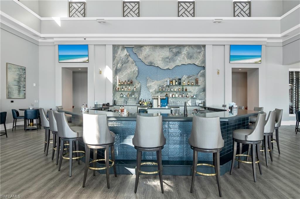 Bar with dark countertops, a high ceiling, and open shelves