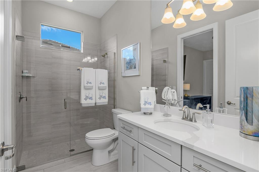 Full bathroom featuring vanity, a stall shower, and hanging lights