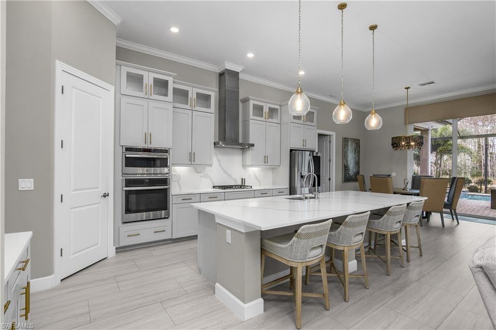 Kitchen with a breakfast bar area, crown molding, a kitchen island with sink, stainless steel appliances, and a chandelier