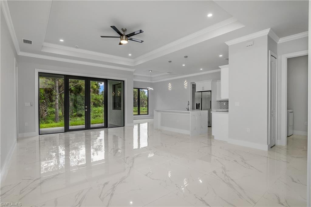 Unfurnished living room with crown molding, ceiling fan, french doors, recessed lighting, and a raised ceiling