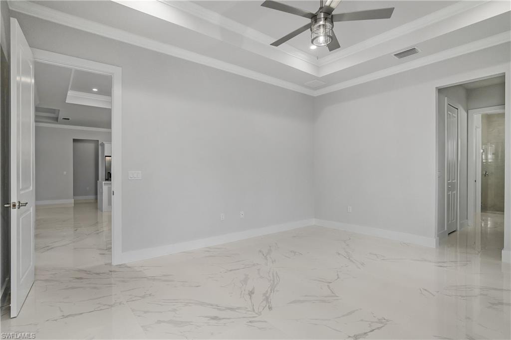 Spare room featuring crown molding, a tray ceiling, light marble finish floors, recessed lighting, and ceiling fan