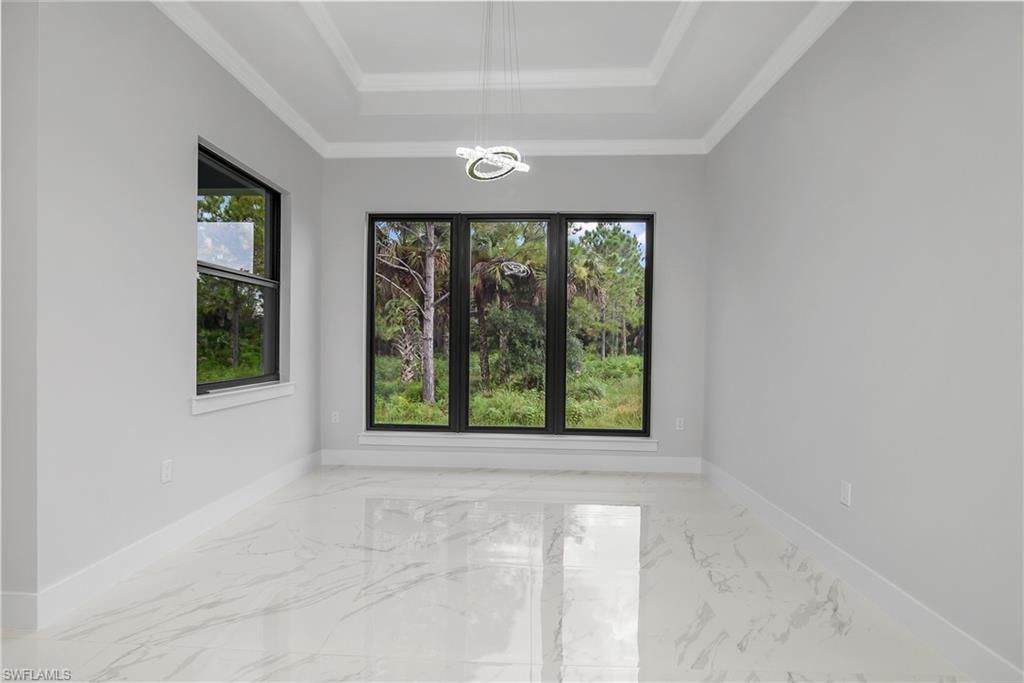 Unfurnished room with light marble finish floors, a chandelier, a tray ceiling, and crown molding