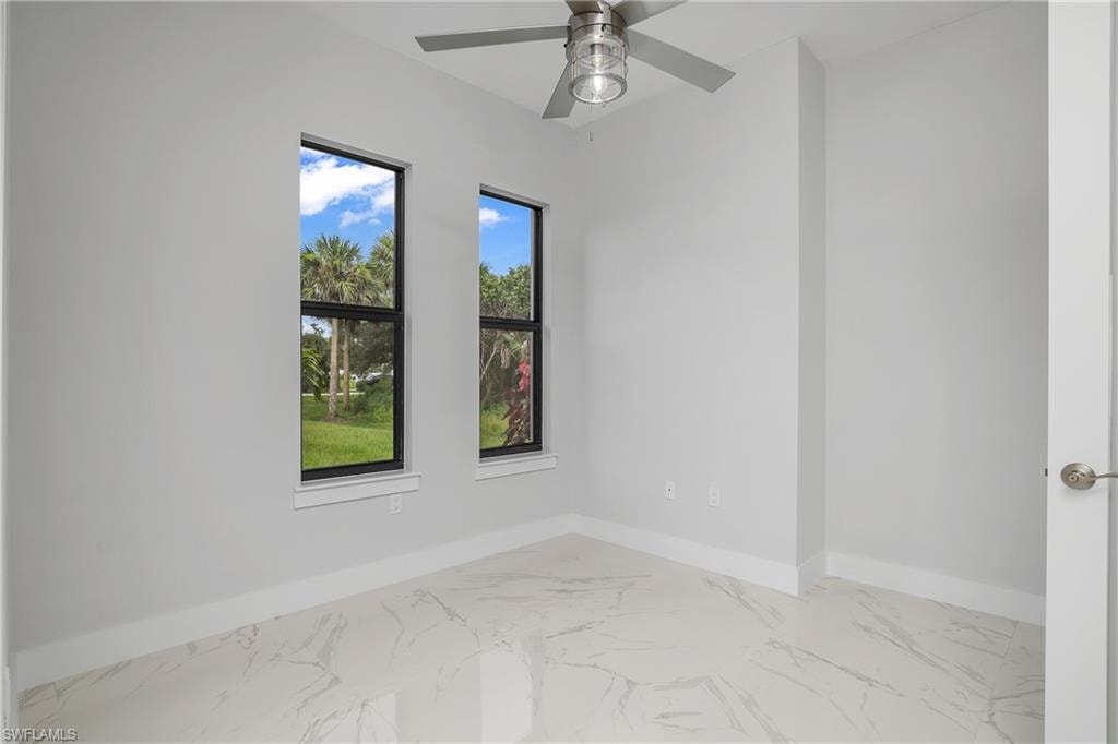 Empty room featuring marble finish flooring and a ceiling fan