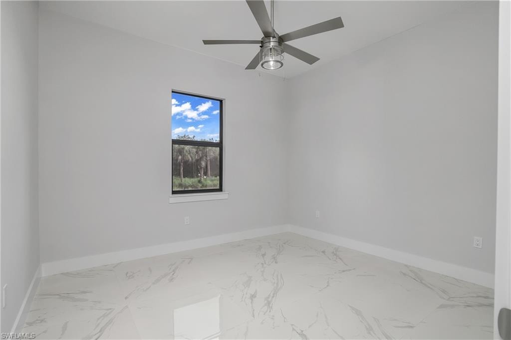 Spare room featuring marble look tile flooring and a ceiling fan