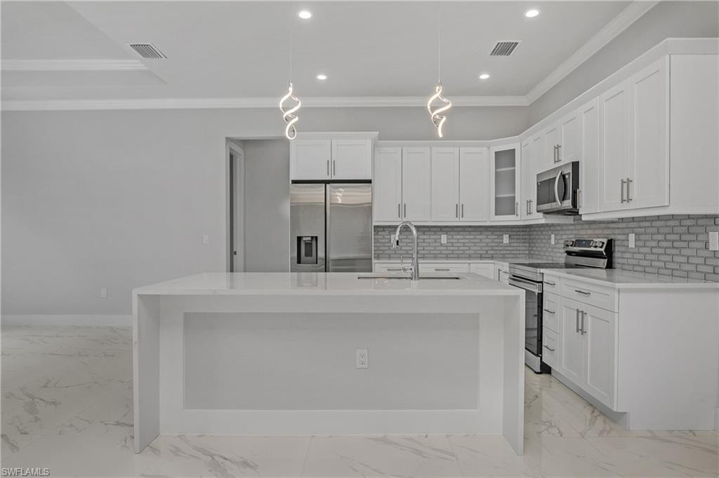 Kitchen featuring stainless steel appliances, decorative light fixtures, light stone countertops, glass fronted cabinets, and ornamental molding