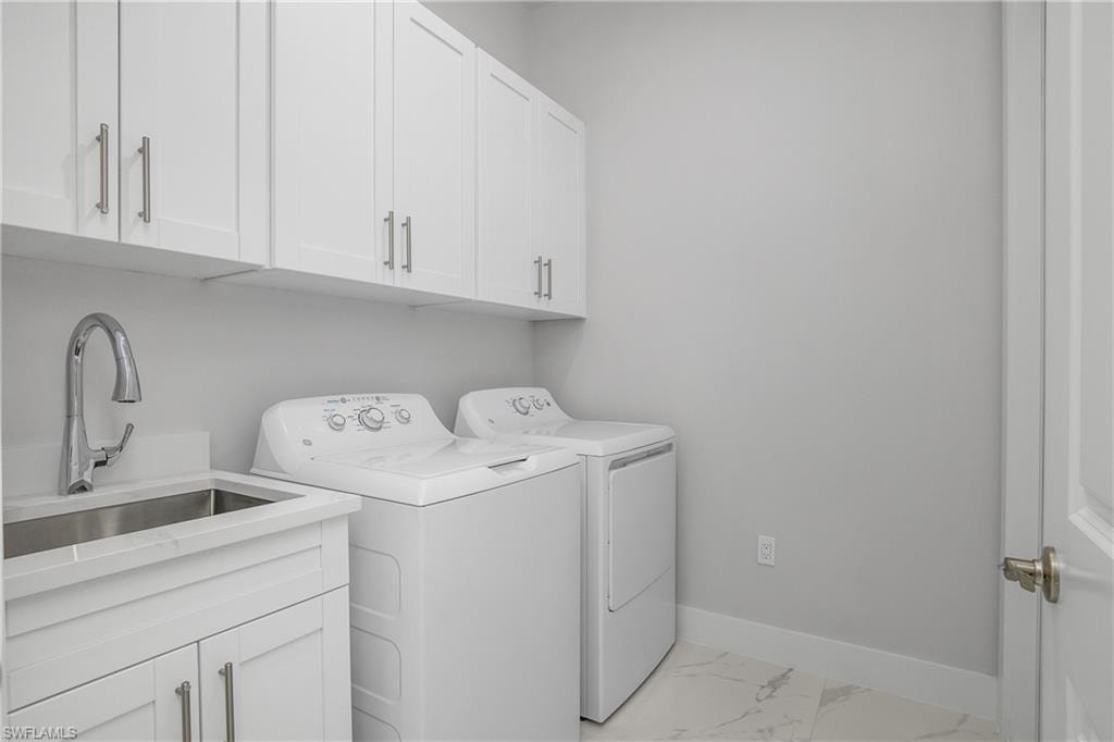 Laundry room with cabinet space, washing machine and dryer, and light marble finish flooring