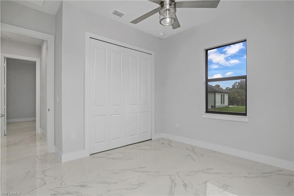 Unfurnished bedroom with light marble finish floors, a closet, and ceiling fan
