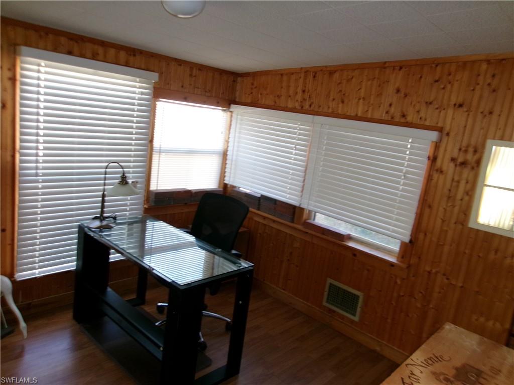 Office with wooden walls and dark wood-style flooring