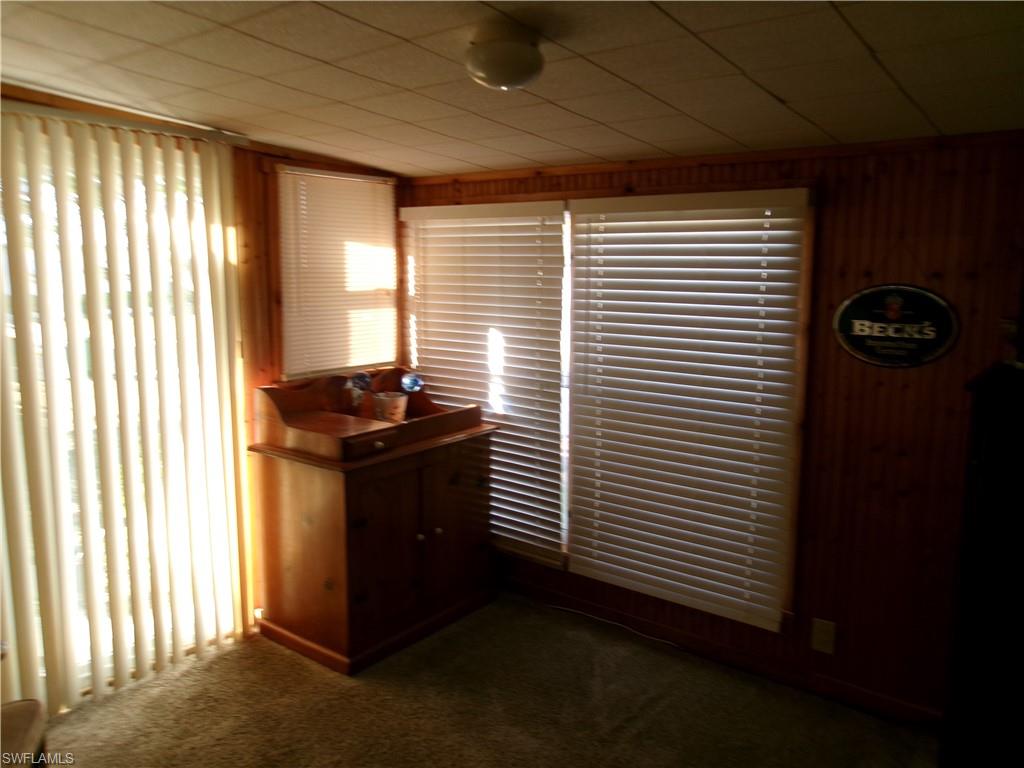 Dining space featuring dark colored carpet and wooden walls