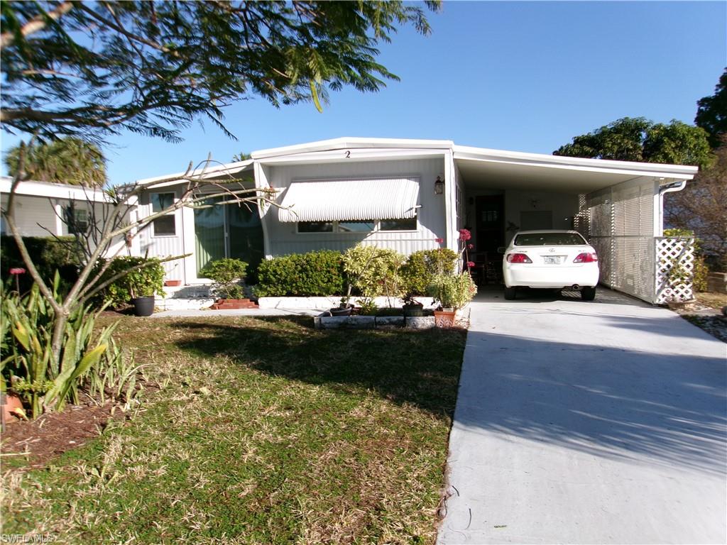 Manufactured / mobile home with concrete driveway, a front yard, and an attached carport