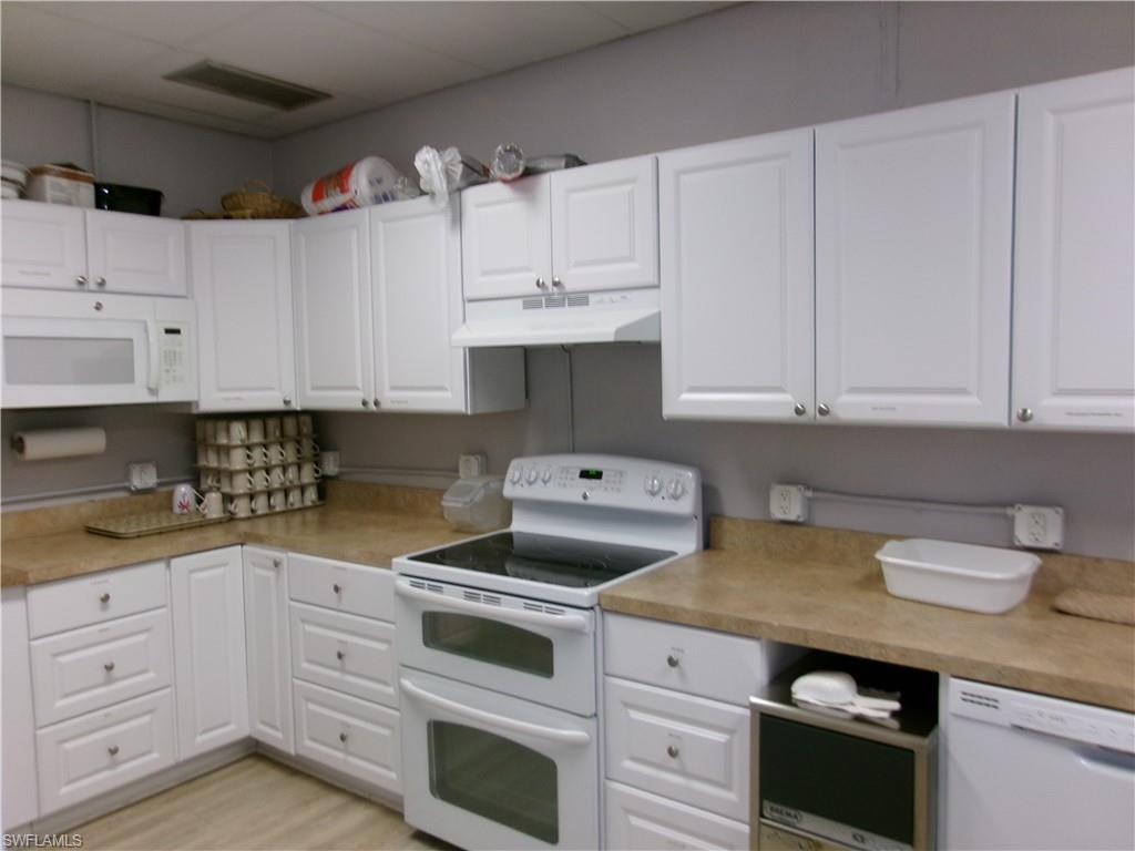Kitchen featuring white appliances, light countertops, white cabinetry, and light wood-type flooring