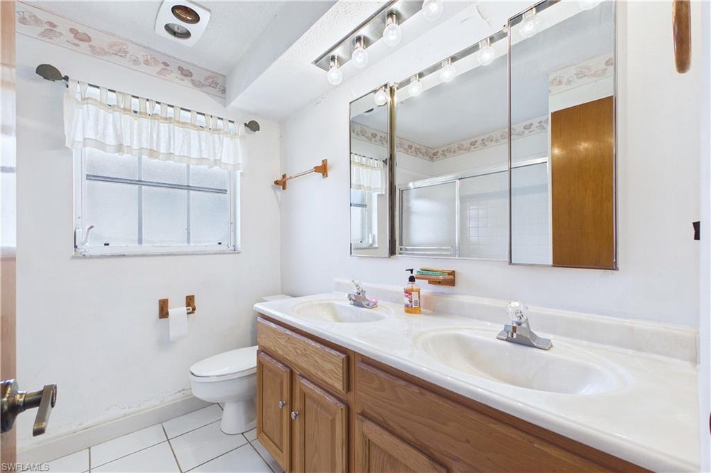 Bathroom with a stall shower, double vanity, and light tile patterned floors