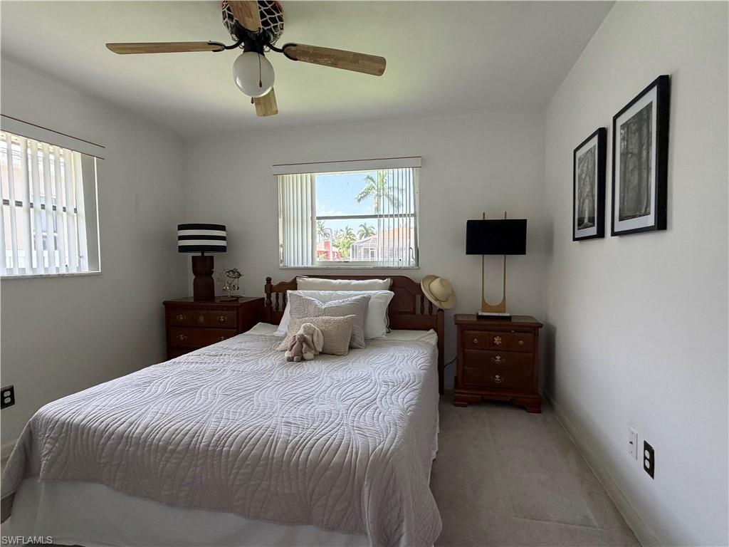 Carpeted bedroom featuring a ceiling fan, two windows with blinds, and white painted walls