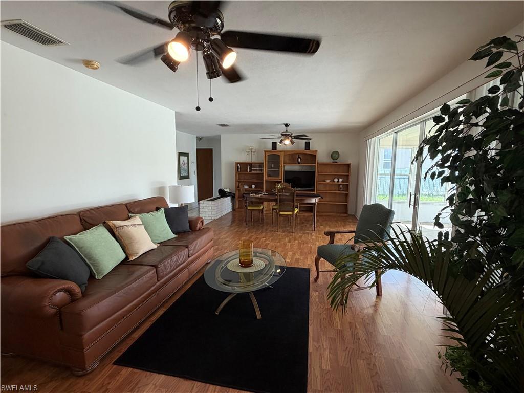 Spacious interior featuring wood-finish flooring, white walls, and a ceiling fan with integrated lighting
