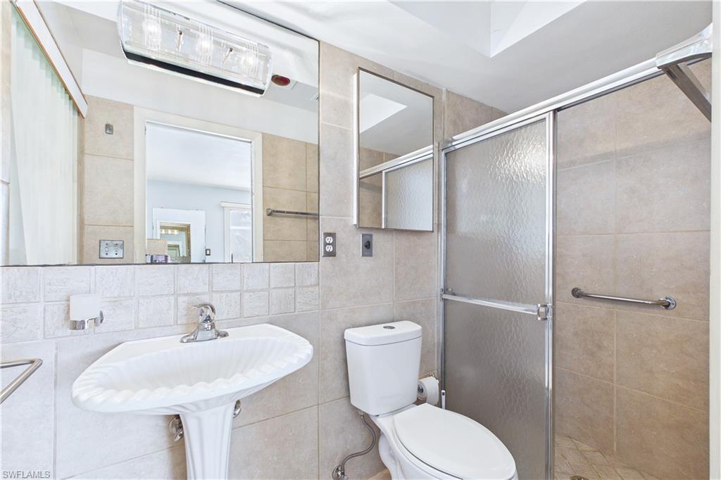 Full bathroom with a shower stall, tile walls, and decorative backsplash