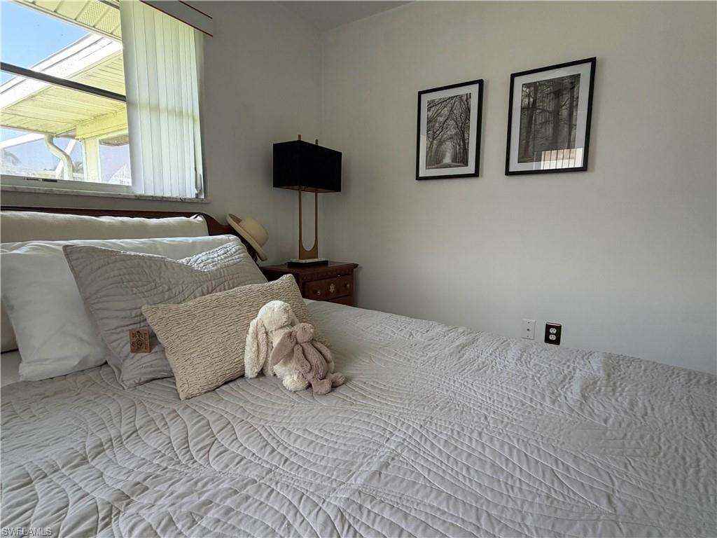 Bedroom featuring a window with vertical blinds, light-toned walls, and a visible electrical outlet