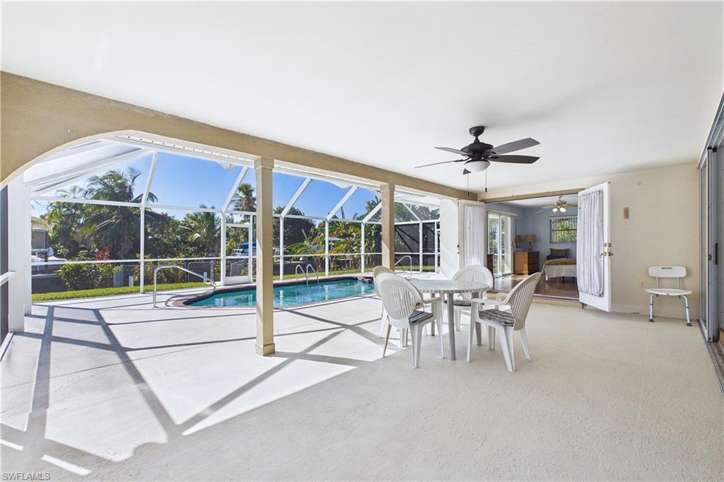 Outdoor pool with a sunroom, a patio, glass enclosure, and outdoor dining space