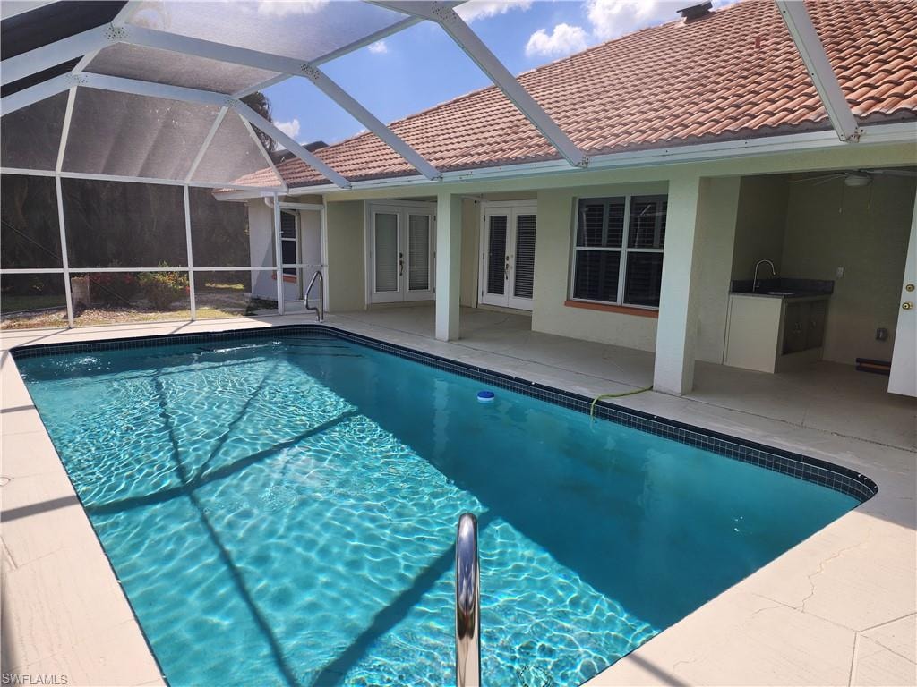 Swimming pool featuring french doors, glass enclosure, a patio area.