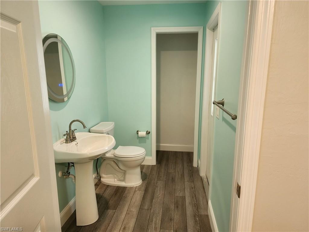 Half bath with toilet and dark wood finished floors