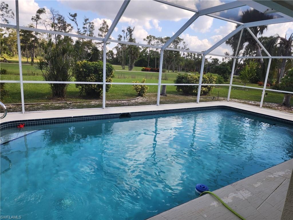 Outdoor pool featuring a sunroom, a lanai, and a yard