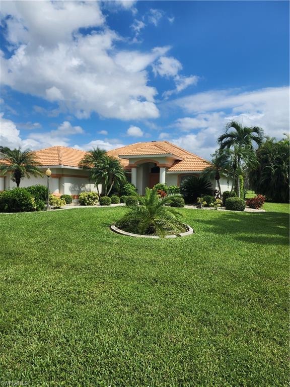 View of front of home with a tile roof, a front yard, and stucco siding