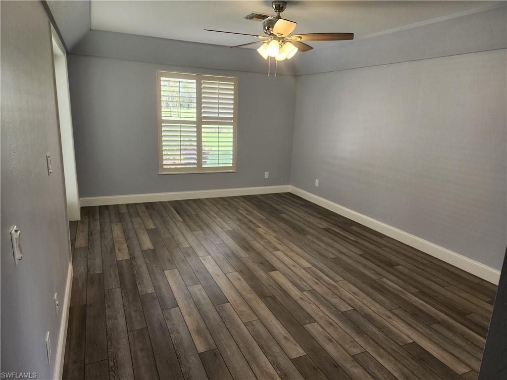 Empty room with ceiling fan and dark wood-style flooring