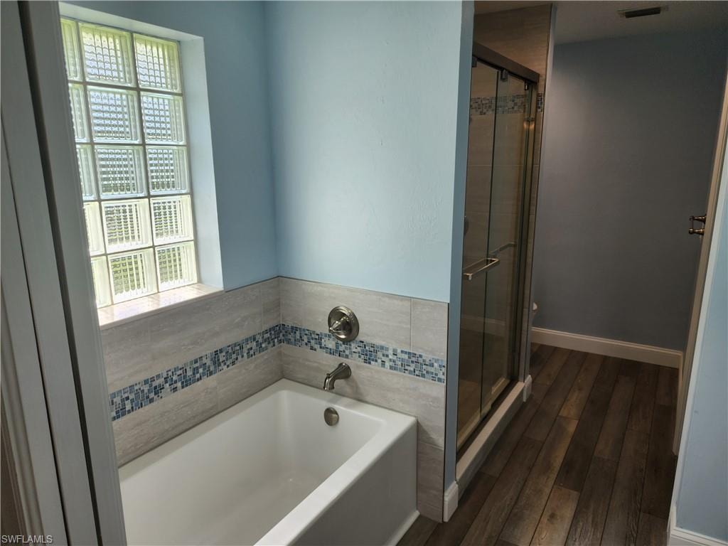 Bathroom featuring a stall shower, a bath, and vinyl wood-type flooring