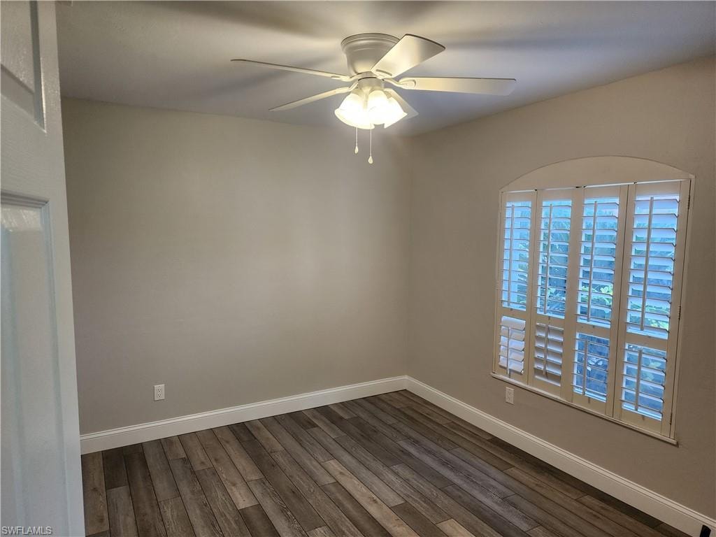 Empty room with dark wood-type flooring and a ceiling fan