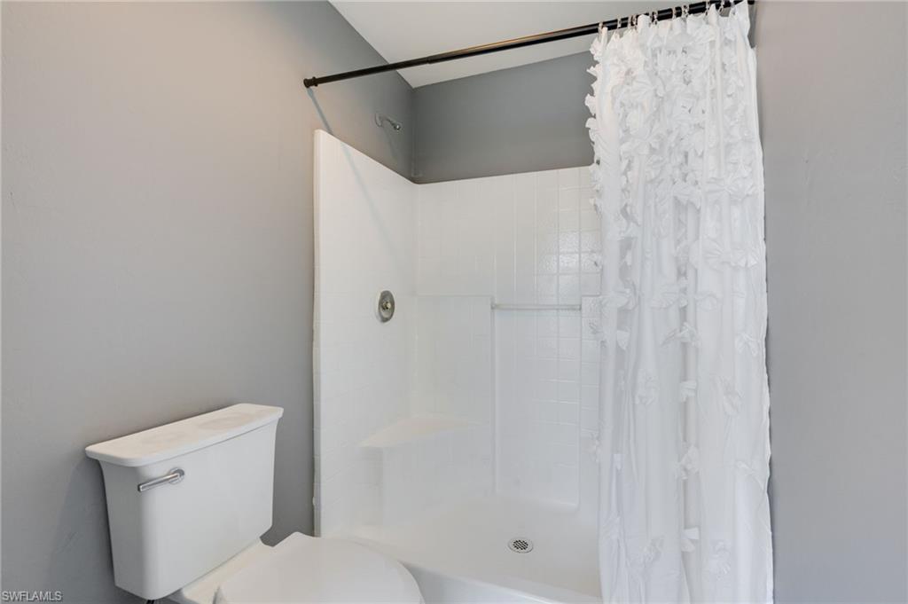 Bathroom featuring toilet and curtained shower