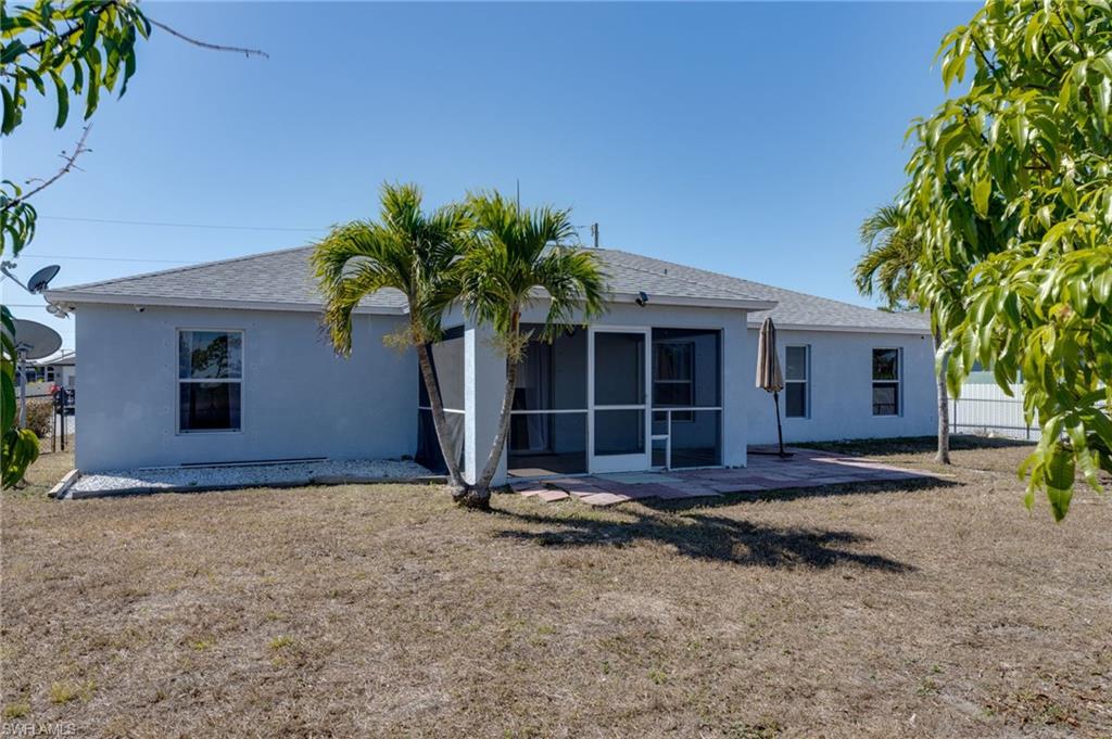 Back of property featuring a patio, stucco siding, a sunroom, and roof with shingles