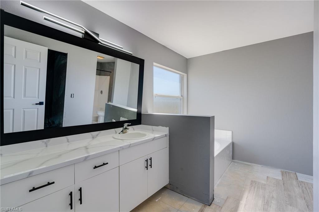Bathroom with vanity, a garden tub, and a shower with shower door